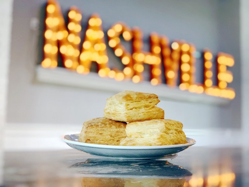 Delicious plate of biscuits from Biscuit Love with a sign of Nashville in the background.