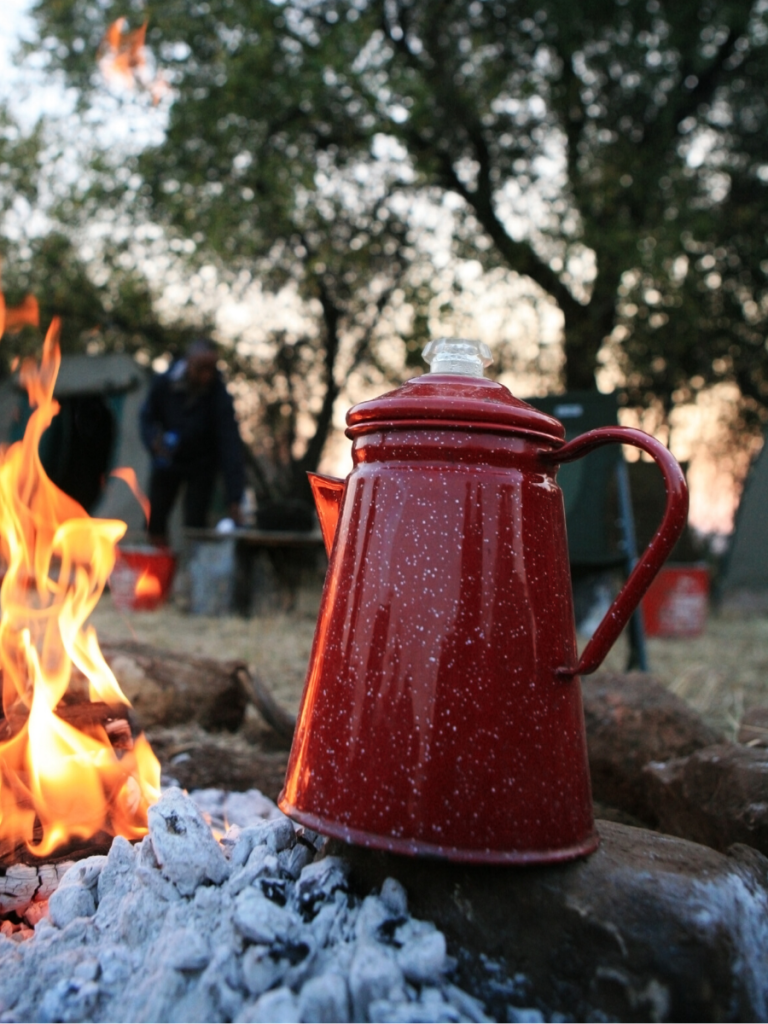 a red percolator by the campfire