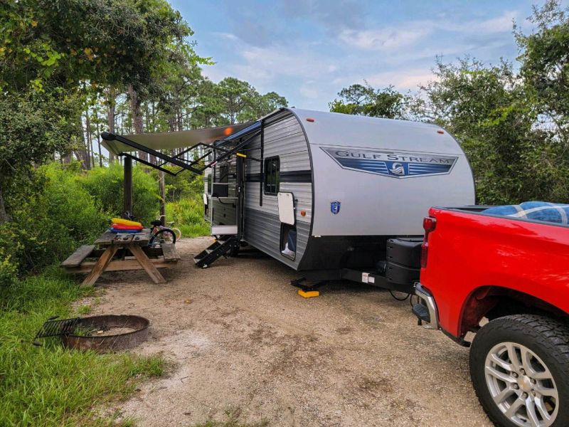 A red chevy silverado hauling a gulf stream camper trailer at a campground. Camping in a camper trailer, RV, 5th Wheels. 