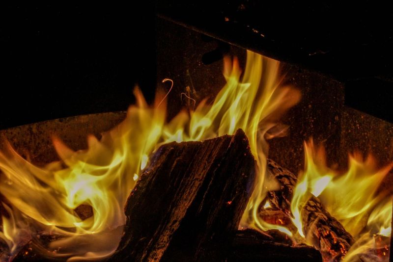 A campfire photo of a log surrounded by yellow and orange flames. Proper Campfire Etiquette