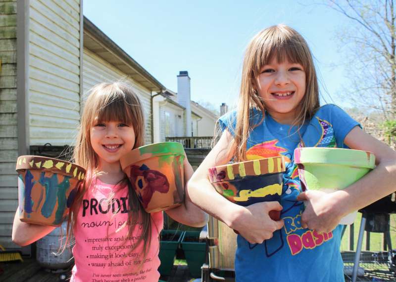 kids painting ceramic pots and gardening