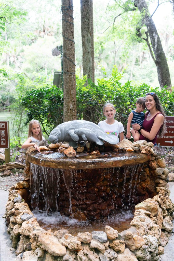 Family posing for a picture by the manatee fountain at Homosassa Springs State Park. 