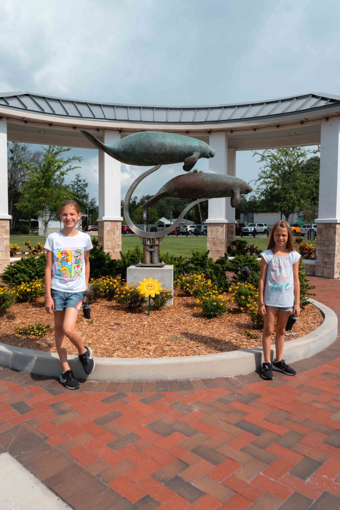 Two girls posing next to a manatee statue in Crystal River. 