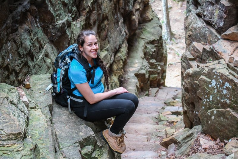 Photo of a woman sitting on the edge of a slot canyon area in Tennessee at Stone Door. Posted on a outdoor hygiene for girls 101 guide that shares tips on how to stay clean and healthy outdoors. 