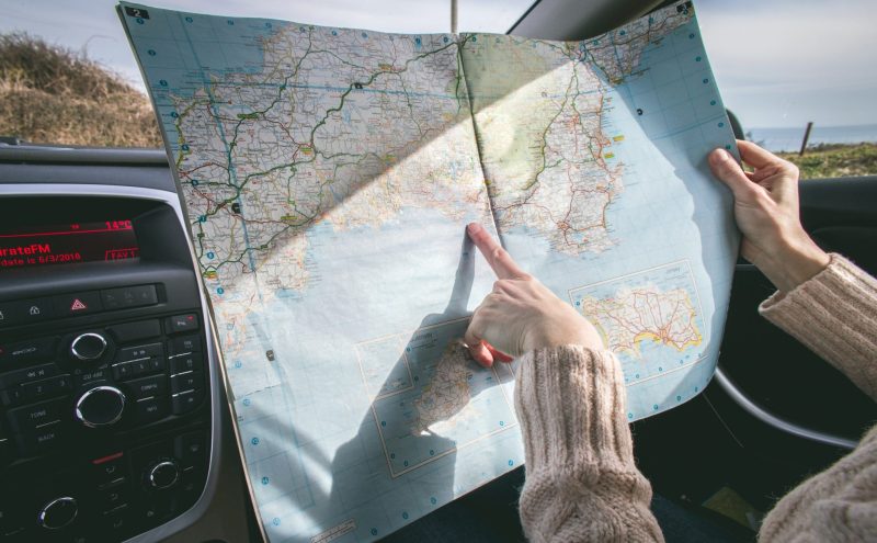 a woman holding a map during a road trip and reading her route