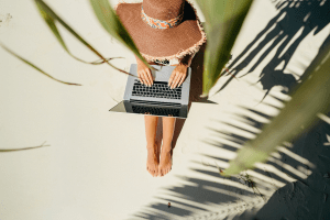 A woman sitting on the sand during a travel agent work trip. Published on an article that teaches others how to become independent travel agents and how to travel more as a travel agent.