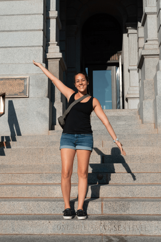 A woman (Jessica Tejera) standing at the mile high step at Denver, Colorado. Published on an article that teaches others how to become independent travel agents and how to travel more as a travel agent. 