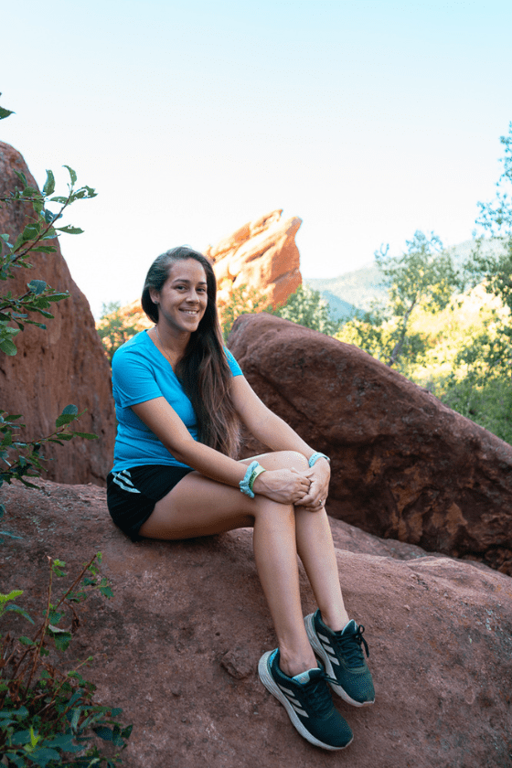 A woman (Jessica Tejera) sitting on a rock at Red Rocks Amphitheater and Park in Colorado. Published on an article that teaches others how to become independent travel agents and how to travel more as a travel agent. 