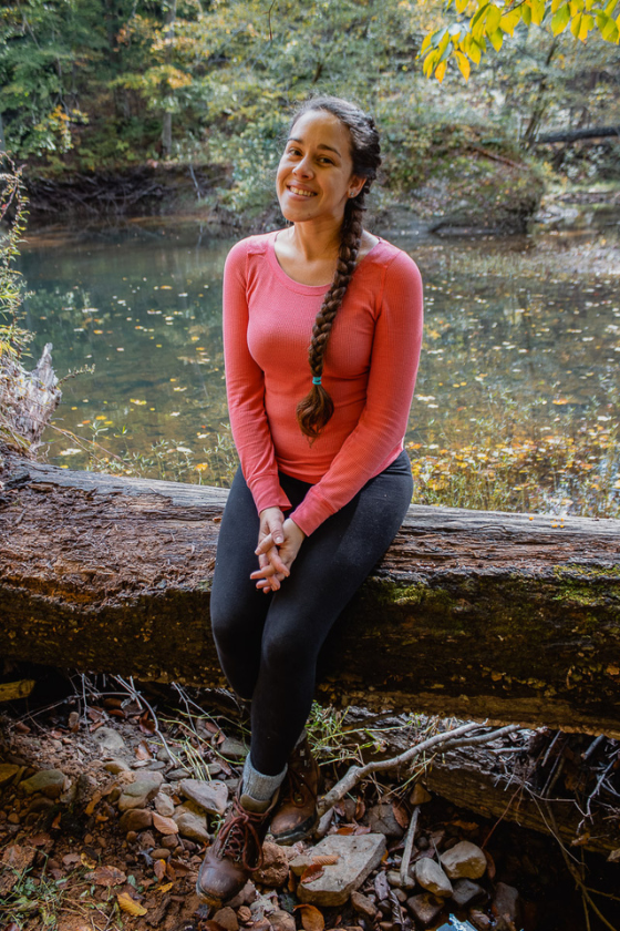 A woman (Jessica Tejera) sitting on a log during a hike at Shawnee National Forest in Illinois. Published on an article that teaches others how to become independent travel agents and how to travel more as a travel agent. 