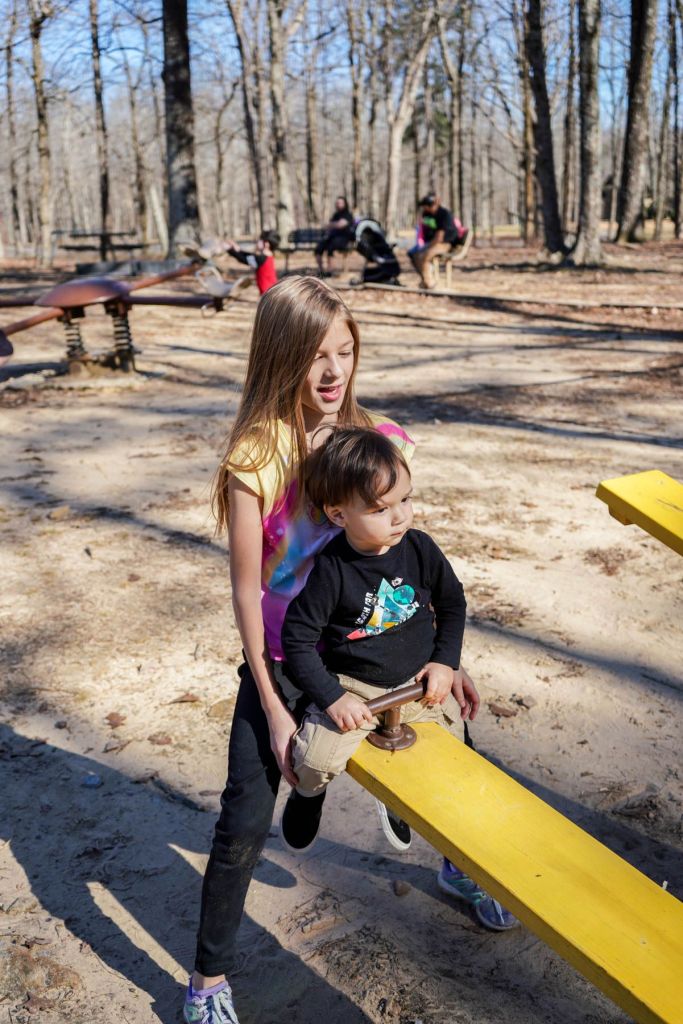 a girl and a boy playing on a seesaw at the playground in Huntsville, Alabama