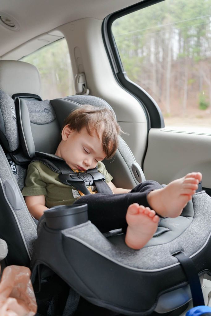 a toddler sleeping in their car seat during a road trip