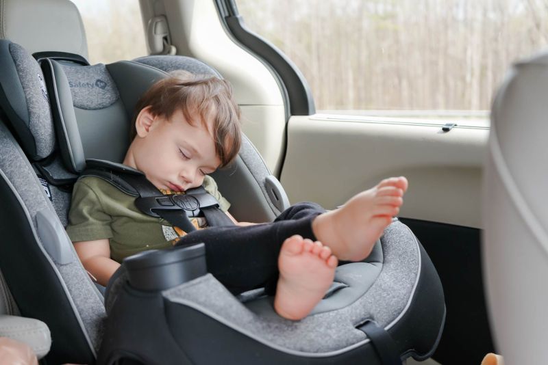 a baby sleeping in his car seat during a family road trip