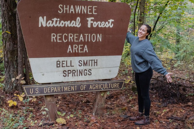 A woman standing by the Shawnee National Forest sign in Illinois.