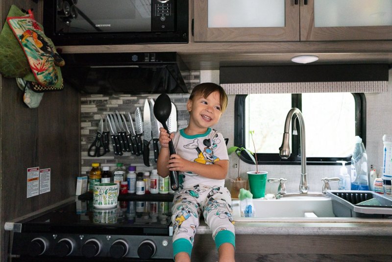 a boy holding a cooking spoon very to start cooking with mom