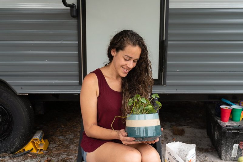 a woman gardening holding a plant that she just transplanted into a new pot. 