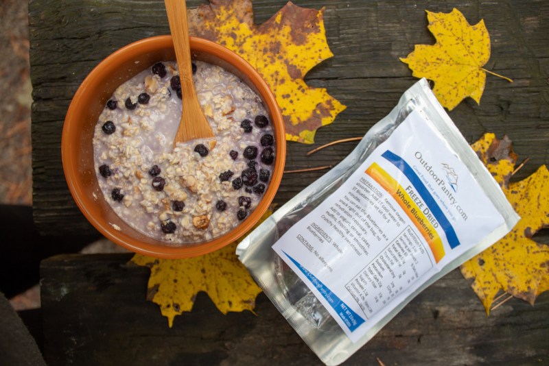 instant oatmeal and dehydrated blueberries cooked during a camping trip in the fall. Orange and yellow leaves outdoors.