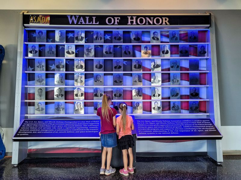 two girls learning about honorable scientists, engineers, and astronauts on the wall of honor 