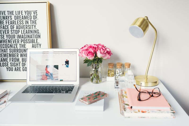 white desk with laptop macbook frame pink flower gold lamp planner notebook books reading glasses gifts for bloggers